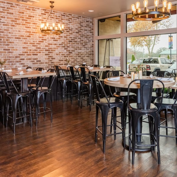 RANGE kitchen & tap interior with high-top tables, black stools, brick walls, and large windows.